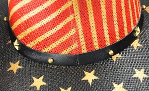 Detail eines Western-Strohhuts mit rot-gelbem Geflecht und Lederband mit Sternen