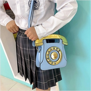 Detail of light blue vintage rotary phone crossbody bag featuring a golden dial and handle