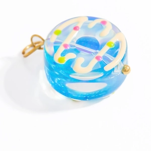 Detail of blue donut glass pendant with colorful sprinkles and golden metal bail