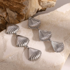 Detailed close-up of triple scalloped silver earrings displayed on natural stones