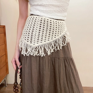 Detail of cream crochet lace waist belt with hollow rhombus patterns and long tassels