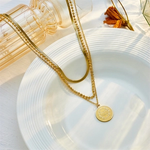 Layered gold chain necklace featuring snake chain, bead strand and round coin pendant