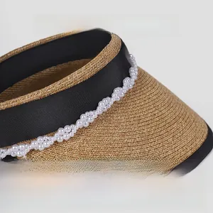 Dettaglio della paglia di carta beige con nastro nero e perle sul cappello estivo