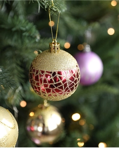 Close-up of a red and gold textured Christmas ball ornament with glitter details