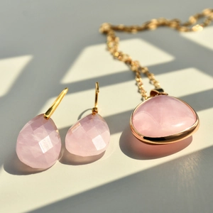 Detailed view of pink quartz necklace and drop earrings set with gold-plated bezel setting