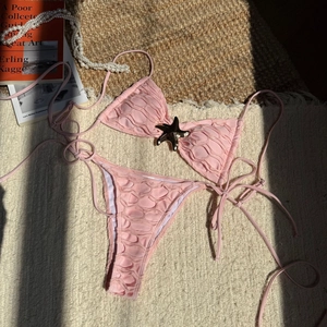 Detailed macro shot of textured pink bikini fabric and golden starfish metal buckle