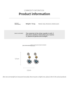 Detail view of vintage heart earrings with blue rhinestones and pearls on white backdrop