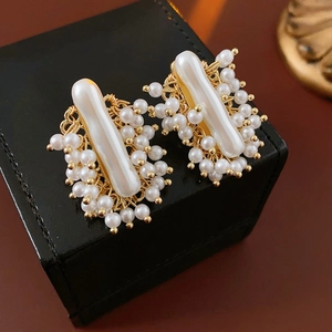 Gros plan détaillé des boucles d'oreilles perles baroques tissées en fil d'or