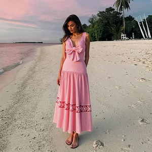 Rosa gestreiftes Maxikleid mit großer Schleife und rotem Blumendruck am Strand