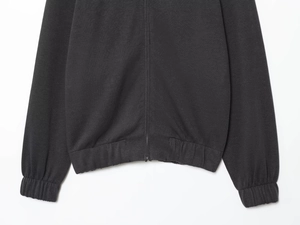 Detail of ribbed hem and elastic cuffs on dark gray knit sweatshirt with zip-up design