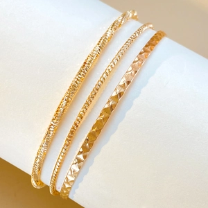 Three-piece gold minimalist bangles set featuring twisted rope and hammered texture designs