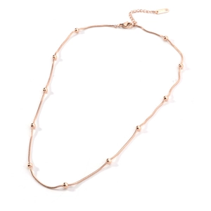 Detail of rose gold snake chain necklace featuring seven beads and lobster clasp closure