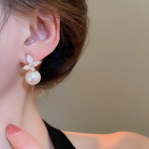 Gros plan d'élégante boucle d'oreille papillon rose avec perle blanche sur modèle