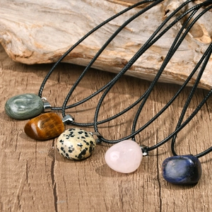 Detail of diverse natural stone pendants including tiger eye and quartz on leather cords