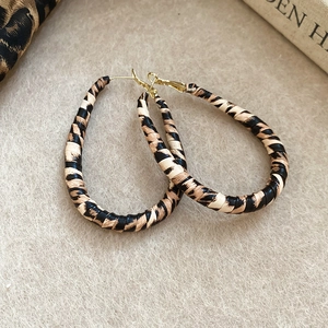 Detail of vintage C-shaped leopard print earrings featuring gold hooks on beige felt