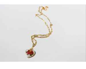 Detail of vintage heart pendant with red rose enamel and pearls on golden necklace