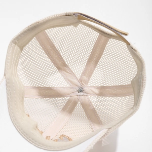 Detail view of breathable mesh structure and reinforced stitching on a beige kids cap