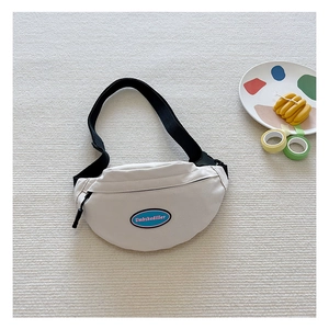 Detail view of cream canvas waist bag with adjustable black strap on a textured white rug