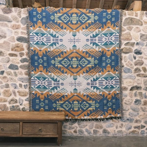 Bohemian Aztec woven picnic blanket with tassels displayed on a vintage wooden bench