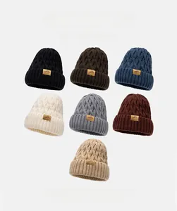 Detail view of thickened knit beanies showing ribbed texture and leather patch logos