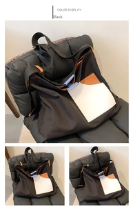 Detail view of the black canvas tote bag showing its color-blocked front pocket design