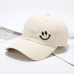 Beige katoenen baseballpet met zwart geborduurde smiley gezien vanuit een hoek van 45 graden