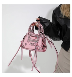 Detail of metallic pink patent leather bag with silver studs and woven handles