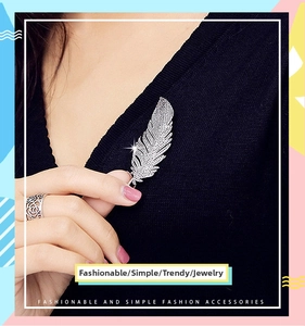 Close-up of a silver zircon feather brooch pinned on a black knit collar for styling