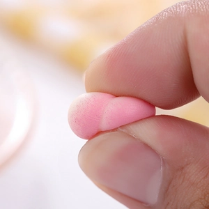 Macro shot of a pink TPR peach squishy toy being squeezed to show soft elastic texture