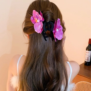 Elegant purple orchid hair claw clip with pearls on brown hair from a back view