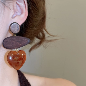 Close-up of model wearing wood and amber resin heart earrings in vintage ethnic style