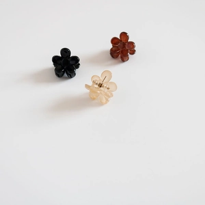 Vue détaillée de trois mini pinces à cheveux en résine en noir, ambre et tons beige clair