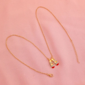 Close-up of golden ballet shoe pendant with sparkling crystals and red enamel detail