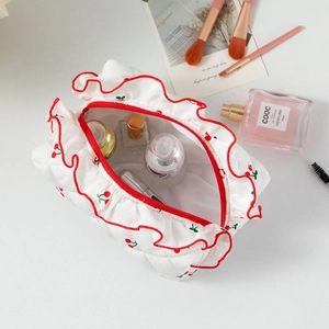 Détail d'une trousse de maquillage matelassée à cerises avec des volants rouges