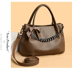Detail of brown leather tote bag with lychee texture, bow decor, and thick metal chain