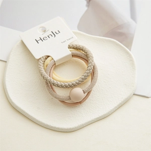 Close-up of three beige elastic hair ties on display card with gypsum tray