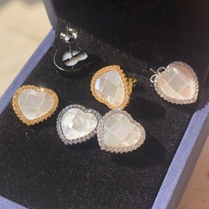 Détail de boucles d'oreilles cœur en nacre et pendentifs avec strass en boîte à bijoux