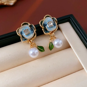 Detail of gold floral earring with blue enamel, sparkling rhinestones and pearl drop