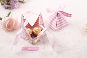 Detail of pink pyramid gift boxes with floral patterns and satin ribbons for wedding candy