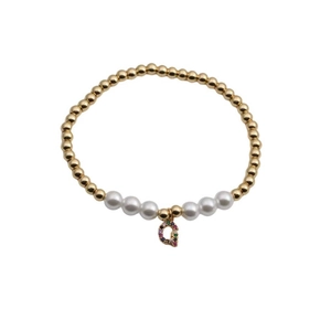 Detail of beaded bracelet with gold metal beads, white pearls and a colorful crystal Q charm