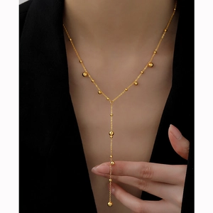 Elegant gold Y-shaped tassel necklace with minimalist beads worn on a chic black blazer