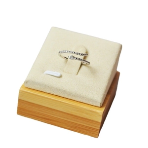 Minimalist silver snake-shaped open ring with pavé diamonds on a beige suede display