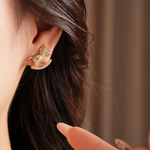 Close-up of a sparkling gold horse-shaped earring with crystals on a model's ear