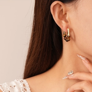 Gros plan d'un mannequin portant des boucles d'oreilles dorées avec perles œil de tigre