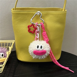 Close-up of fluffy white plush doll charm with pink lips hanging on a yellow bag