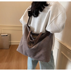 Detail of dark canvas tote bag worn by a model in a minimalist home setting with natural light