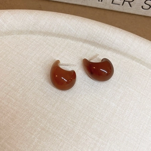 Détail de boucles d'oreilles en résine marron sur plateau avec aiguille en argent