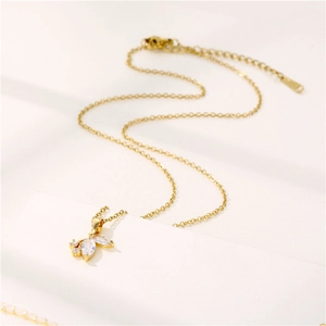 Elegant gold stainless steel necklace featuring a crystal butterfly pendant on beige background