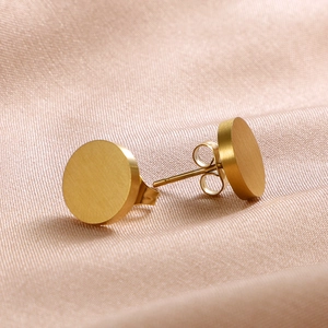 Close-up of golden round brushed stainless steel studs on elegant pink silk fabric
