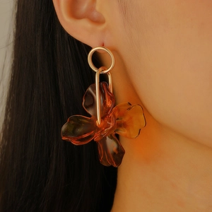 Detailed view of amber flower drop earring with golden metal hoop on model ear